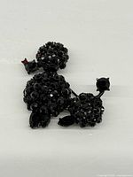 Front view of poodle brooch showing black rhinestone coverage and red eye