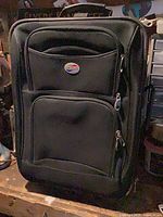 Front view of black softside carry-on suitcase showing exterior pockets and handle