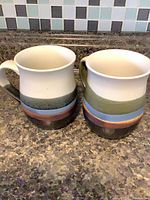 Front view of both multicolour band ceramic mugs