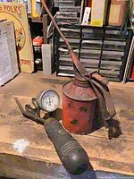 Battery tester gauge and oil can on workbench
