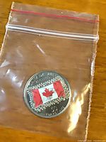 Front of coloured Canadian flag 50-cent coin in bag
