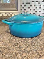 Full view of turquoise Dutch oven with lid on countertop