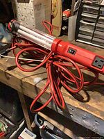 Full view of Designers Edge LED trouble light with coiled red extension cord on workbench