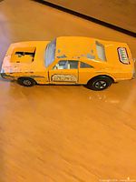 Left side view of orange toy car showing missing motor and chipped paint
