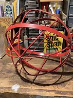 Full view of red metal orb sculpture on workbench