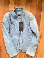 Full view of light blue leather jacket laid flat showing front zipper and pockets