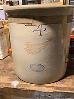 Full view of cream stoneware crock showing blue "4" mark, red wing logo, and rim reinforcement