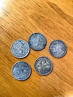 Five silver threepence coins reverse side showing crowned numeral 3 and wreath designs