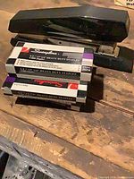 Black stapler on wood surface, three Swingline staple boxes stacked