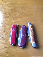 Three closed pocket knives showing handles, colors, size comparison