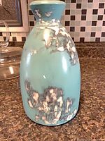 Front view of turquoise ceramic vase with distressed patches
