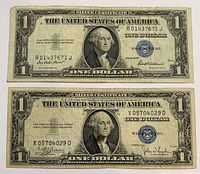 Front of both $1 blue seal certificates showing series letters, serial numbers and wear