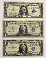Front of three $1 blue seal silver certificates with serial numbers visible