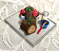 Top view of miniature Yule Log ornament on silver pan with accessories