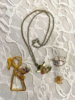 All jewelry pieces laid out on lace background: necklace and three pins