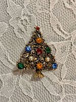front view of Christmas tree rhinestone brooch on lace background