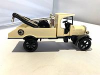 Left side view of cream diecast tow truck showing bed, boom, hook and State Farm decal