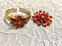 Cuff watch closed beside poinsettia brooch on lace background