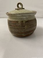 Front view of lidded stoneware pot showing glaze and carved banding