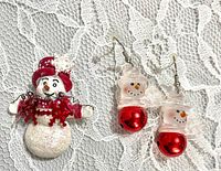 Snowman brooch and pair of glass snowman earrings displayed on lace background