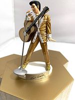 Front view of Elvis Presley plastic figure showing pose, gold suit, guitar and mic stand
