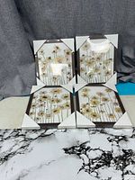 Four framed floral prints with protective corners displayed upright