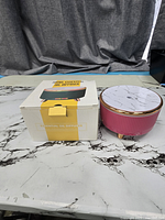 Pink ribbed essential oil diffuser with marble-pattern lid beside original box