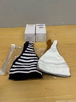 Assorted stripe and white baby hats with two unopened boxes visible