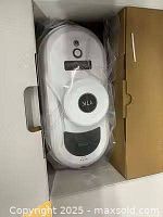 Robot in box with plastic wrap and accessory tray visible