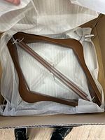Open box showing brown wooden hangers inside protective wrap