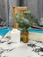 Full view of eucalyptus arrangement in amber vase with box and styrofoam