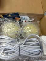 Box contents showing two round LED lights, remote, and coiled power cable