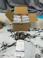 Open box showing six packaged LED step lights with accessories and two remotes in front
