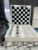 Open foam tray showing glass chessboard and shot glasses