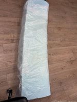 Top view of full-length rolled mattress topper in plastic