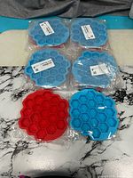 Six of the ten individually wrapped honeycomb bee silicone molds, red and blue colors visible