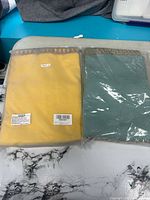 Both packaged pillow cases, yellow and sage, front view