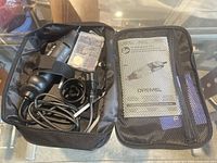 Dremel rotary tool set in soft case showing tool, bits box, power cord, manual
