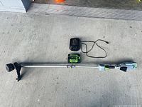 Full view of EGO string trimmer with battery and charger laid out on floor