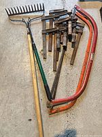 All items: rake, pruning saw, bow-saw frames, pile of bar clamps