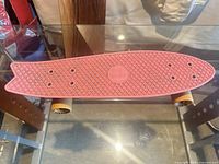 Top view of red-pink Penny Board PE skateboard on glass table