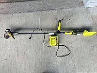 Full view of Ryobi 40V cordless string trimmer with charger attached by cord