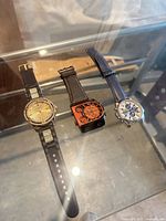 Group shot of three wristwatches laid flat in glass case