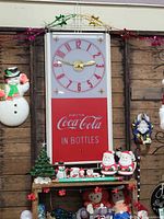 Front view of large Coca-Cola advertising clock showing dial and logo panel