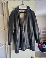 Full view of black leather coat on hanger