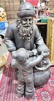 Front view of bronze-tone resin Santa statue with children and toy sack