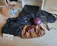 Group view of five bags, purple bowling ball, racket on carpet