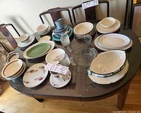 Tabletop view of assorted plates, bowls, cups, teal platter, glass bowls, bake dish
