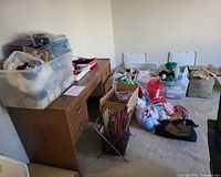 Room view with desk, plastic bins and bags filled with yarn and supplies