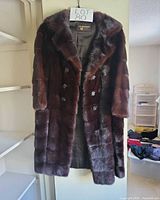 Full view of mahogany fur coat hanging, shows overall condition and length